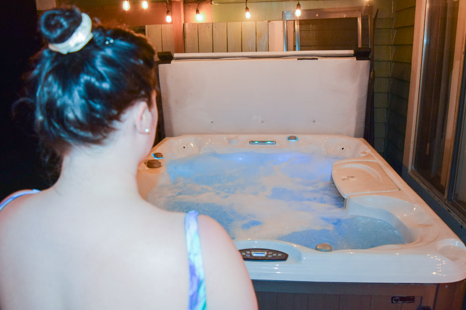 A guest at the hot tub with the water lit blue